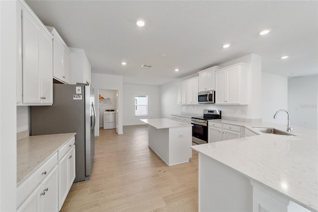 kitchen featuring white cabinets, appliances with stainless steel finishes, a kitchen island, and sink