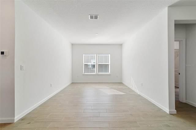 spare room featuring light hardwood / wood-style flooring and a textured ceiling