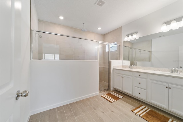 bathroom featuring a textured ceiling, vanity, and a shower with shower door