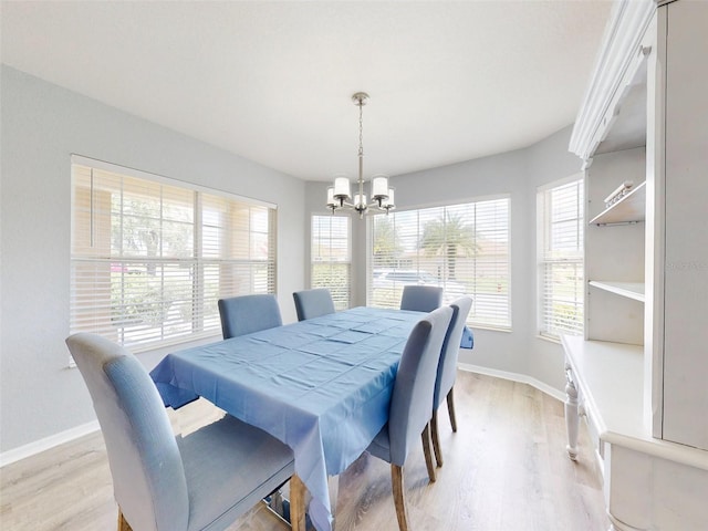 dining space with light hardwood / wood-style flooring, a healthy amount of sunlight, and a notable chandelier