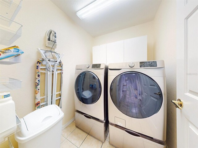 laundry area featuring cabinets, separate washer and dryer, and light tile patterned floors