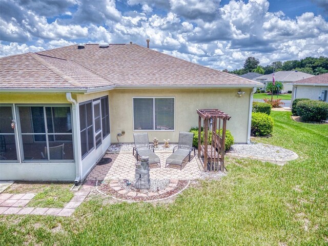 rear view of property with a yard, a patio area, and a sunroom