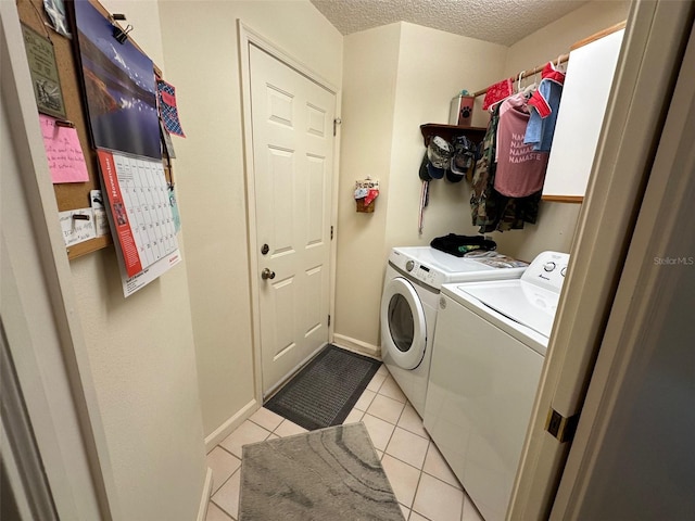 clothes washing area featuring washer and clothes dryer, light tile patterned floors, and a textured ceiling