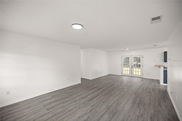 unfurnished living room with a textured ceiling, french doors, and dark hardwood / wood-style floors