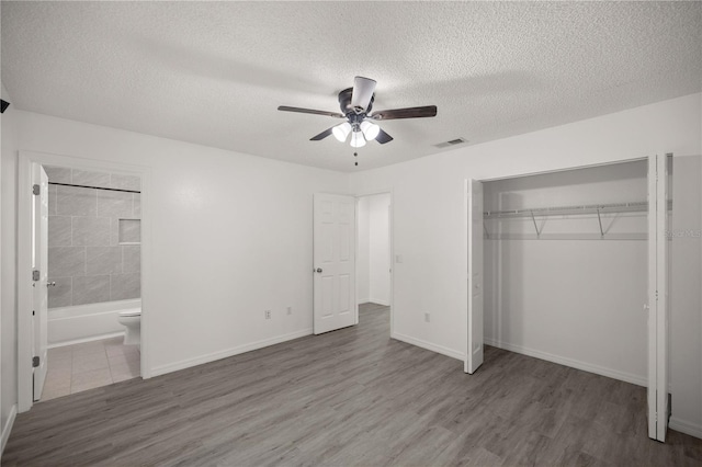 unfurnished bedroom featuring hardwood / wood-style floors, a textured ceiling, a closet, and ceiling fan