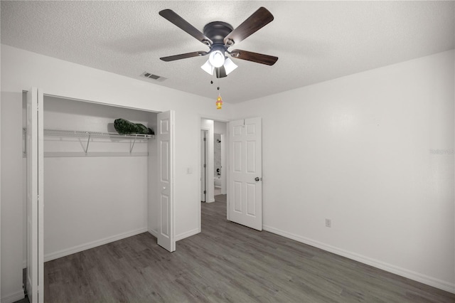 unfurnished bedroom with ceiling fan, a closet, dark wood-type flooring, and a textured ceiling