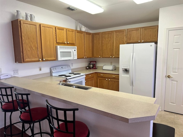 kitchen featuring kitchen peninsula, white appliances, and a breakfast bar