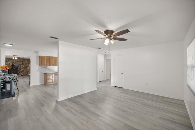 unfurnished room featuring ceiling fan, light hardwood / wood-style floors, and a textured ceiling