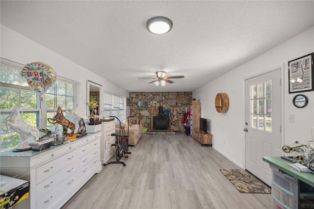 interior space with a textured ceiling, light hardwood / wood-style floors, a wood stove, and a wealth of natural light