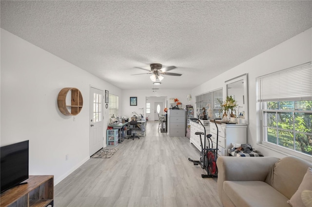 living room with ceiling fan, a textured ceiling, and light wood-type flooring