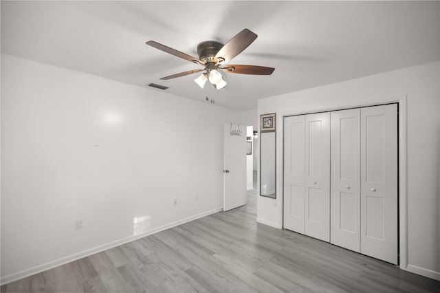 unfurnished bedroom featuring ceiling fan, a closet, and light wood-type flooring