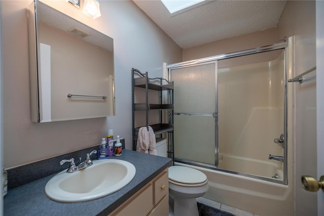 full bathroom with a skylight, vanity, a textured ceiling, enclosed tub / shower combo, and toilet