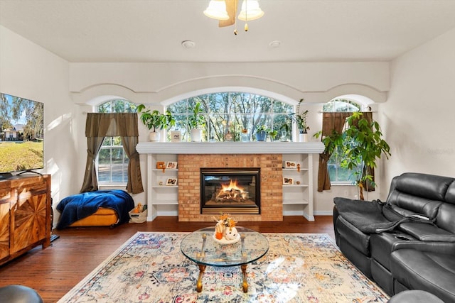 living room with a fireplace, built in shelves, and dark hardwood / wood-style floors