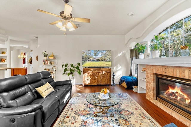 living room featuring dark hardwood / wood-style floors, ceiling fan, built in features, and a fireplace