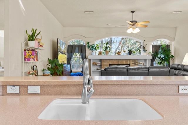 kitchen featuring ceiling fan, a fireplace, and sink