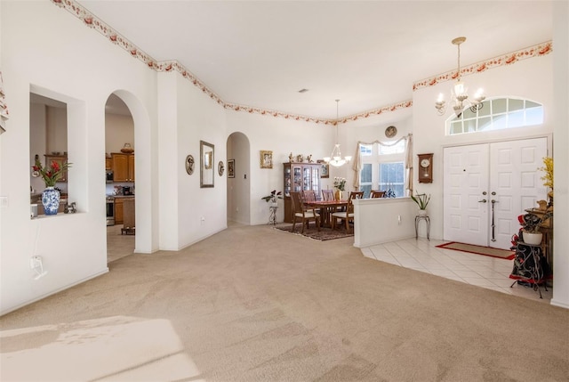 foyer entrance with light carpet and a chandelier