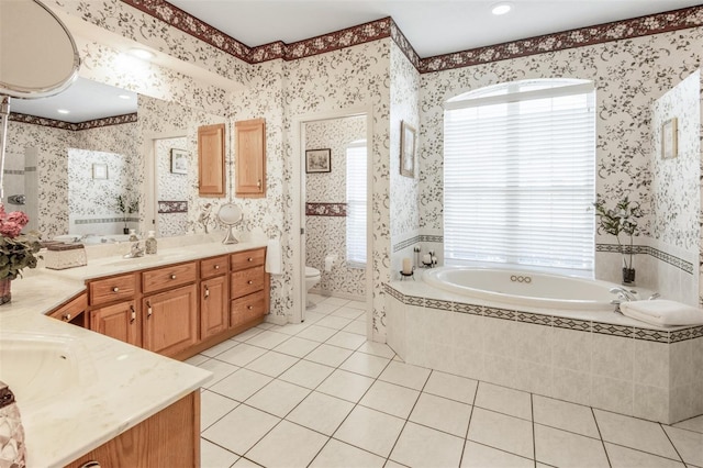 bathroom featuring tile patterned flooring, vanity, a relaxing tiled tub, and toilet