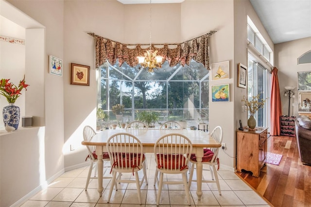 dining space featuring a notable chandelier, light hardwood / wood-style floors, and a towering ceiling