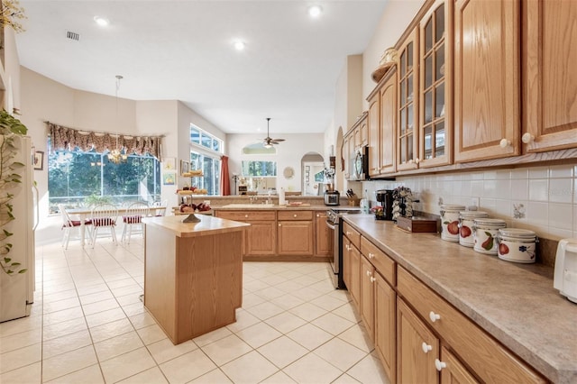 kitchen with pendant lighting, light tile patterned floors, tasteful backsplash, a kitchen island, and stainless steel appliances