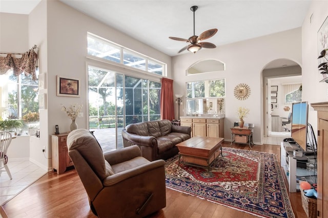 living room featuring light wood-type flooring, plenty of natural light, and ceiling fan