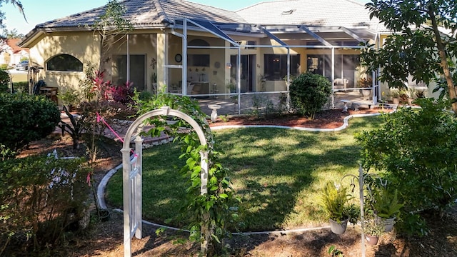 back of property featuring glass enclosure and a yard