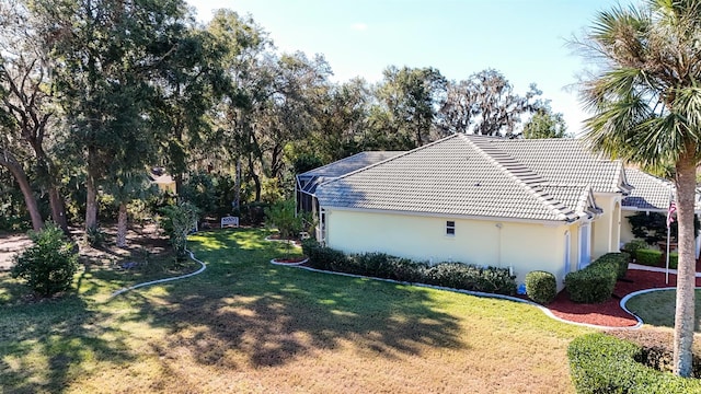 view of property exterior featuring glass enclosure and a lawn