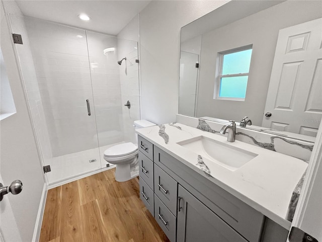 bathroom with hardwood / wood-style floors, vanity, a shower with door, and toilet