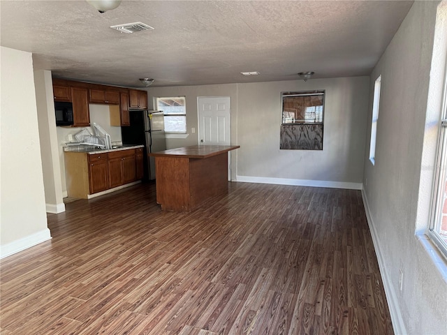 kitchen featuring stainless steel fridge, a center island, dark hardwood / wood-style floors, and a textured ceiling