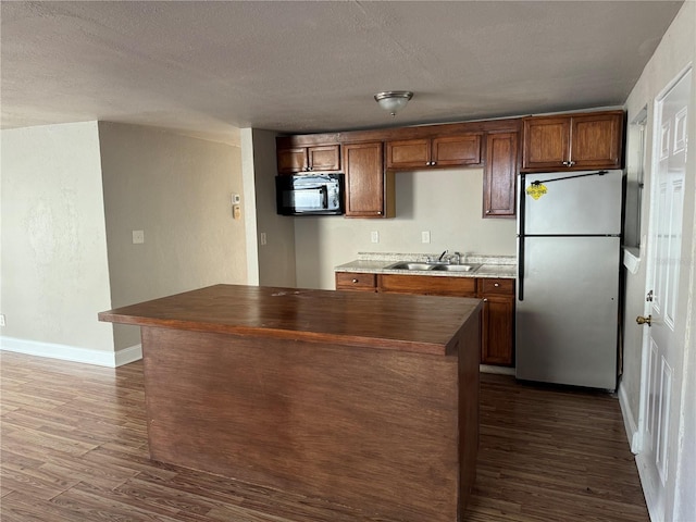 kitchen with stainless steel fridge, dark hardwood / wood-style flooring, a textured ceiling, and sink