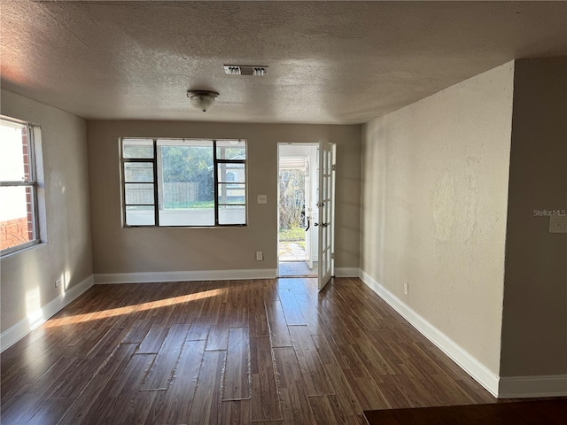 unfurnished room with a textured ceiling and dark hardwood / wood-style flooring