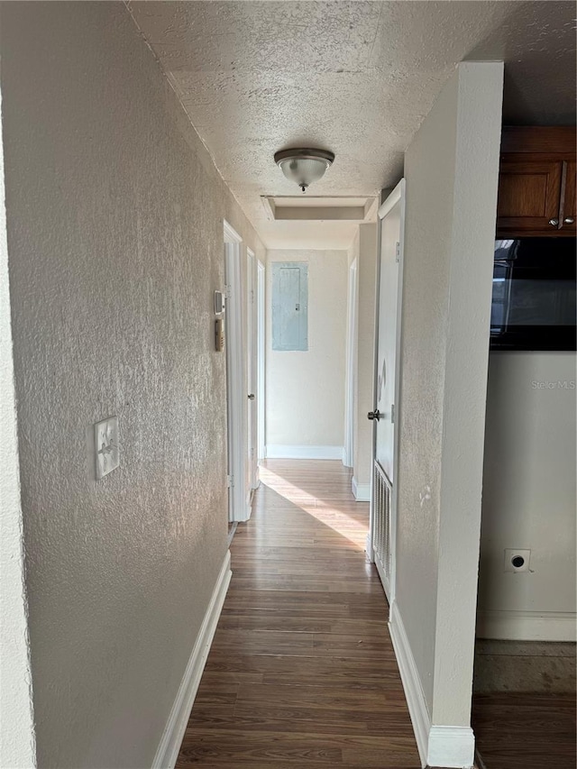 corridor with wood-type flooring, a textured ceiling, and electric panel