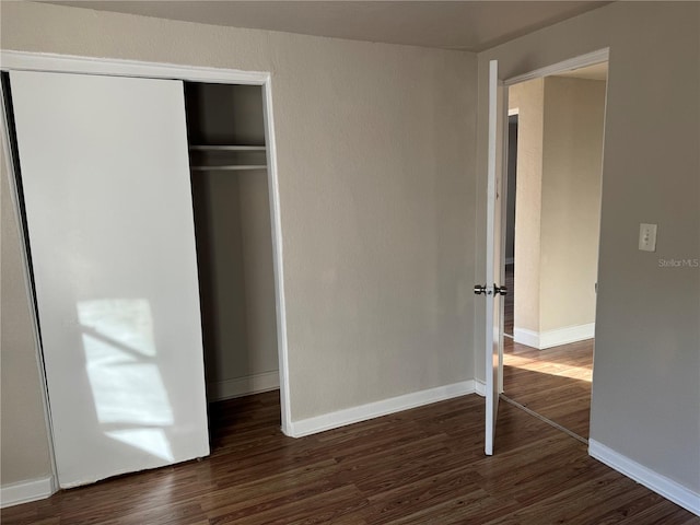 unfurnished bedroom with dark hardwood / wood-style floors and a closet