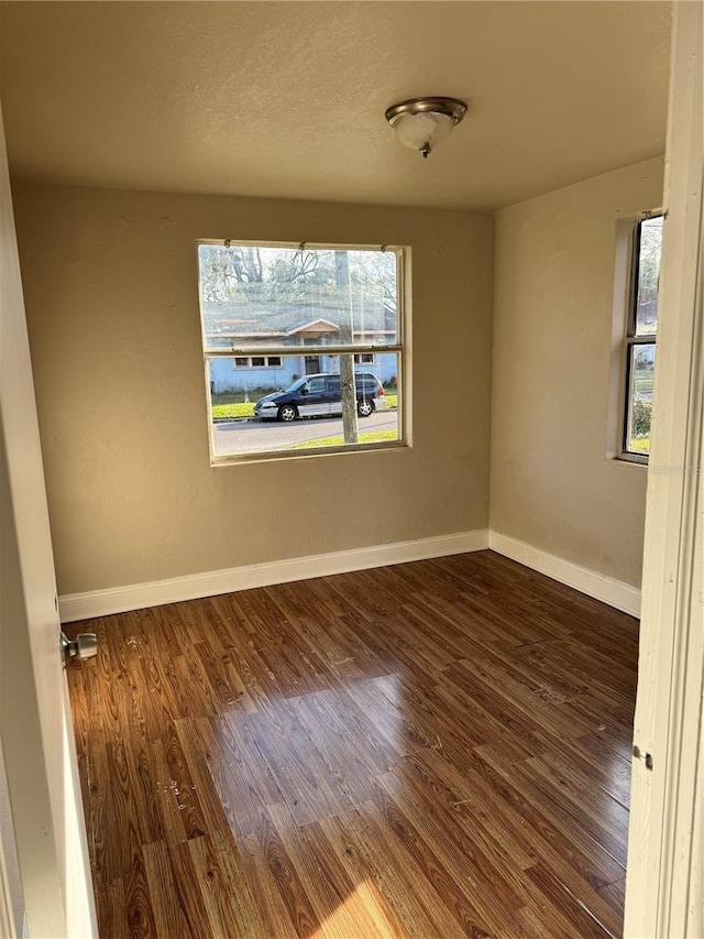 unfurnished room with plenty of natural light and dark wood-type flooring