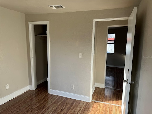 unfurnished bedroom with a walk in closet, dark hardwood / wood-style floors, and a closet