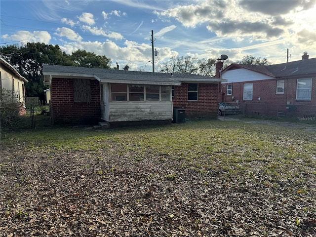 rear view of property featuring a lawn and central AC