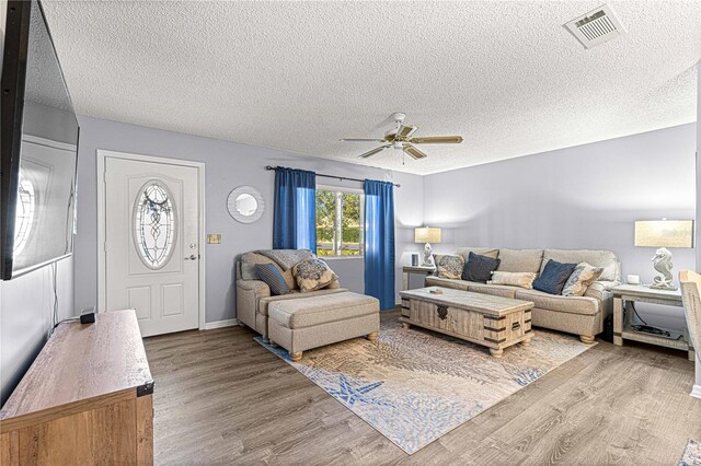 living room featuring a textured ceiling, light hardwood / wood-style floors, and ceiling fan