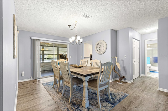 dining area featuring a textured ceiling, an inviting chandelier, and light hardwood / wood-style flooring