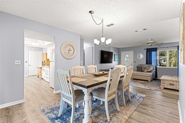 dining space featuring ceiling fan with notable chandelier, a textured ceiling, and light hardwood / wood-style flooring