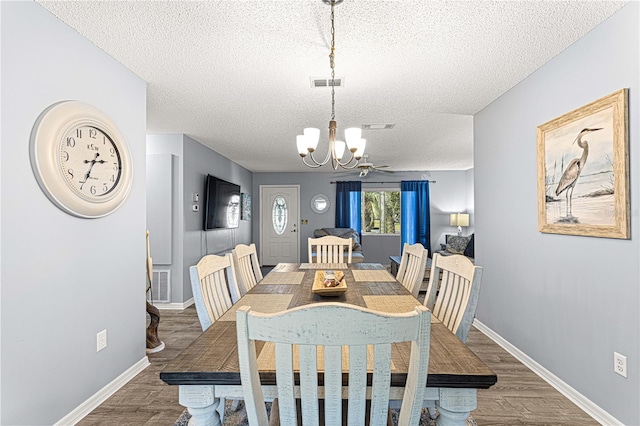 dining space with hardwood / wood-style floors, a textured ceiling, and a notable chandelier