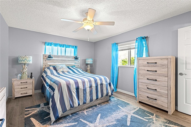 bedroom with a textured ceiling, ceiling fan, and dark wood-type flooring