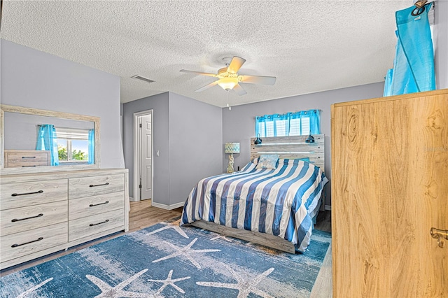 bedroom with hardwood / wood-style floors, ceiling fan, and a textured ceiling