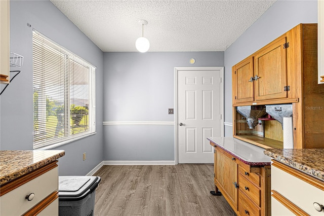 kitchen featuring a textured ceiling, light hardwood / wood-style floors, and dark stone counters