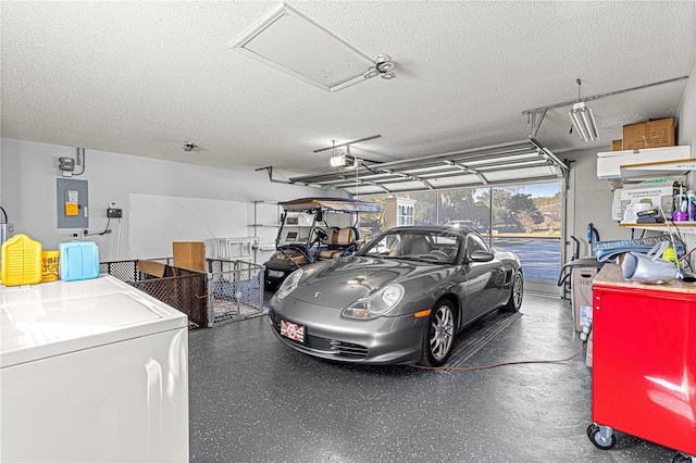 garage with electric panel, a garage door opener, and washer / clothes dryer