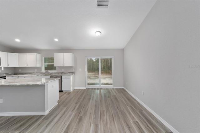 kitchen with baseboards, visible vents, white cabinets, light stone countertops, and stainless steel dishwasher