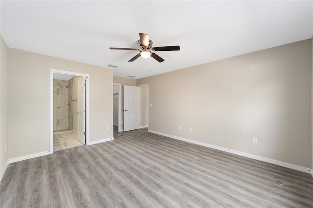 unfurnished bedroom featuring visible vents, baseboards, a ceiling fan, ensuite bathroom, and light wood-style floors