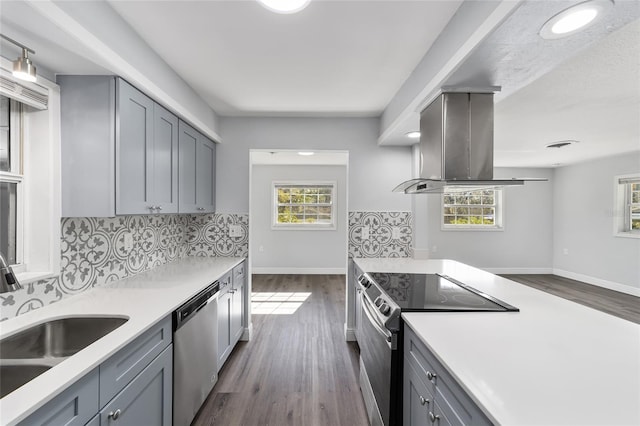 kitchen featuring gray cabinets, island range hood, dark hardwood / wood-style flooring, and appliances with stainless steel finishes