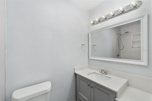 bathroom with a tile shower, vanity, and toilet