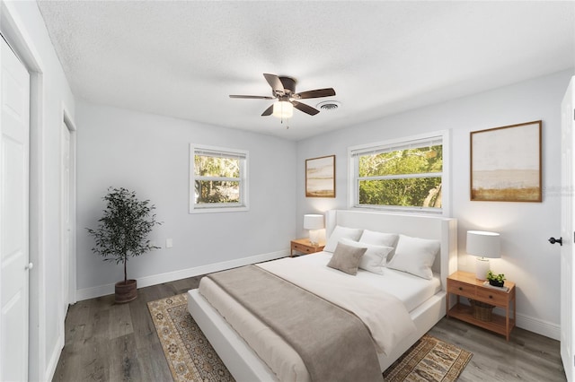 bedroom with ceiling fan, wood-type flooring, a textured ceiling, and multiple windows