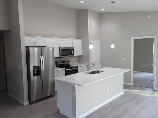 kitchen featuring hanging light fixtures, sink, white cabinets, and stainless steel appliances