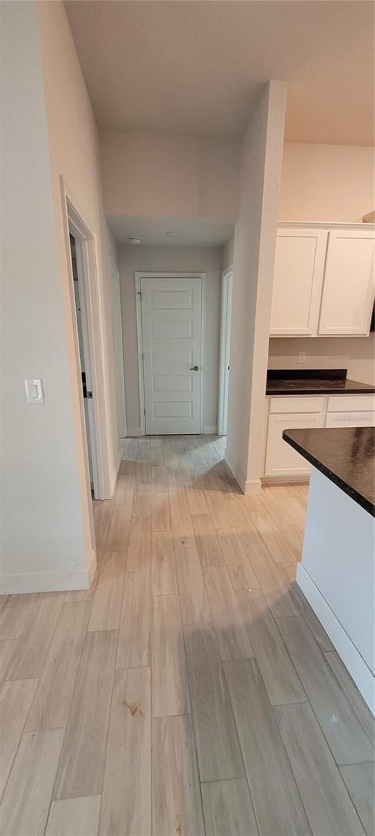 corridor featuring light wood-style floors and baseboards